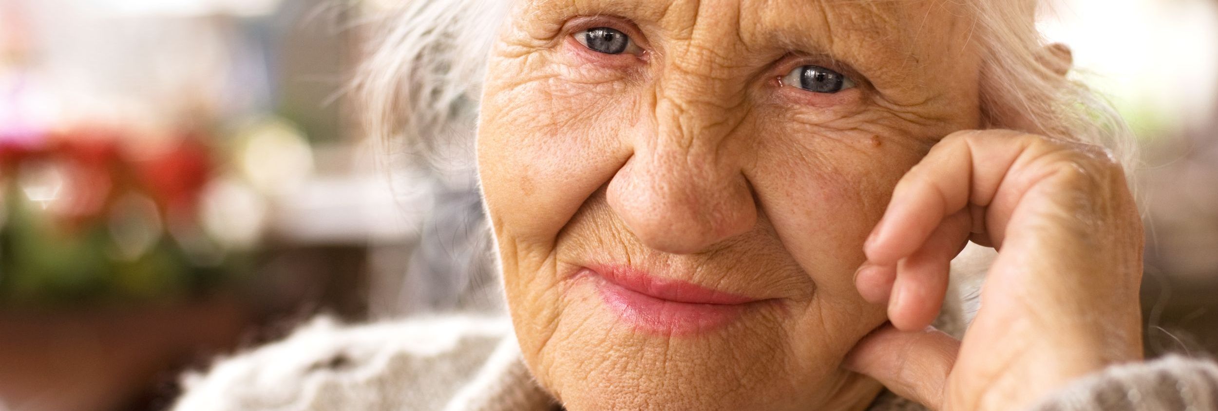 Nahaufnahme einer älteren Frau mit blauen Augen und Hand an der Wange