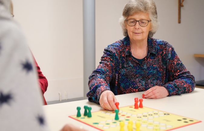 Ältere Frau in Gemeinschaft beim Spielen eines Brettspiels